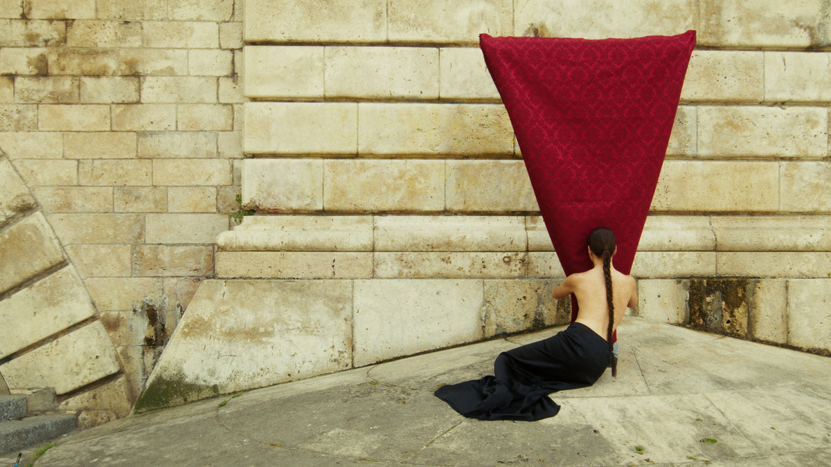 Adelina Bernard pre-campaign Like the Peeling of a Pomegranate woman lying on the ground embracing a red fabric form