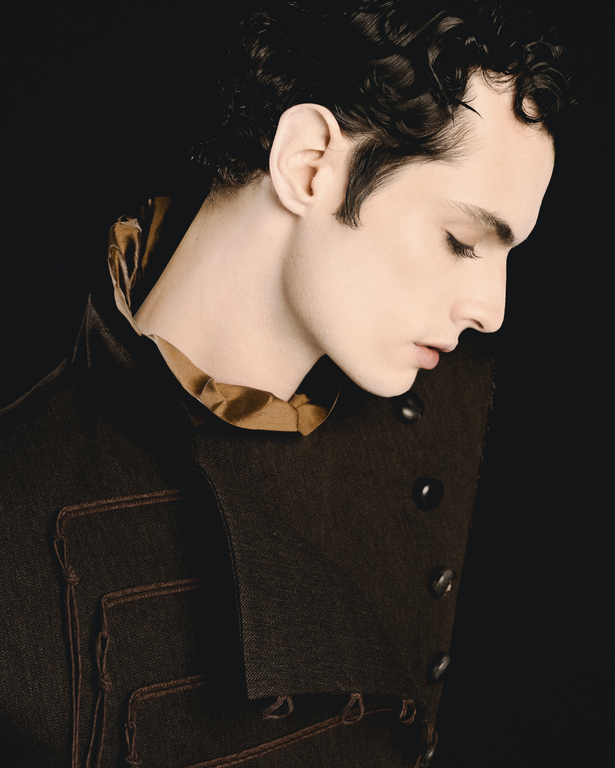 Adelina Bernard SS25 Pulling Strings campaign Close up of man wearing a dark master jacket with a bronze blouse underneath on a black background